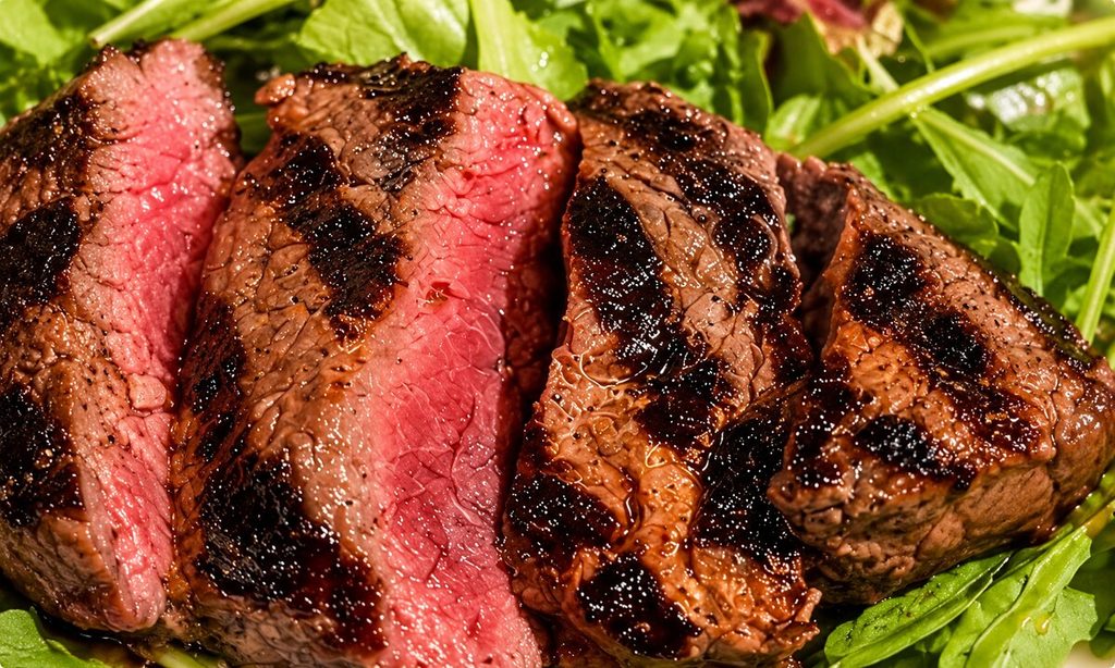 Fette di manzo rosolate all’esterno e rosate al centro, adagiate su un letto di rucola.