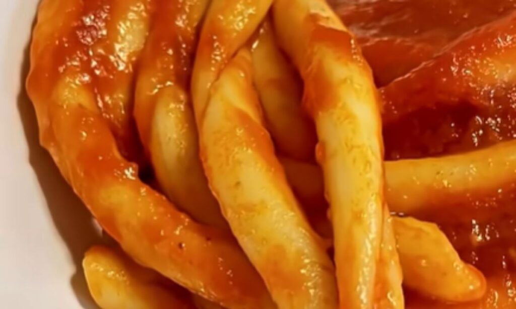 Fusilli al ferretto conditi con sugo di pomodoro e carne.