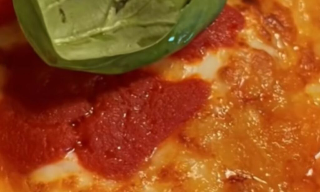 Gnocchi alla sorrentina con superficie gratinata e dorata, pomodoro e basilico, in una ciotola di terracotta.