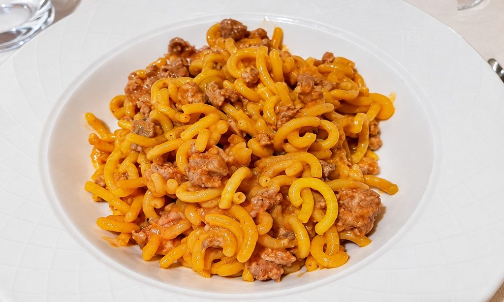 Gramigna con ragù di carne servita su un piatto bianco.