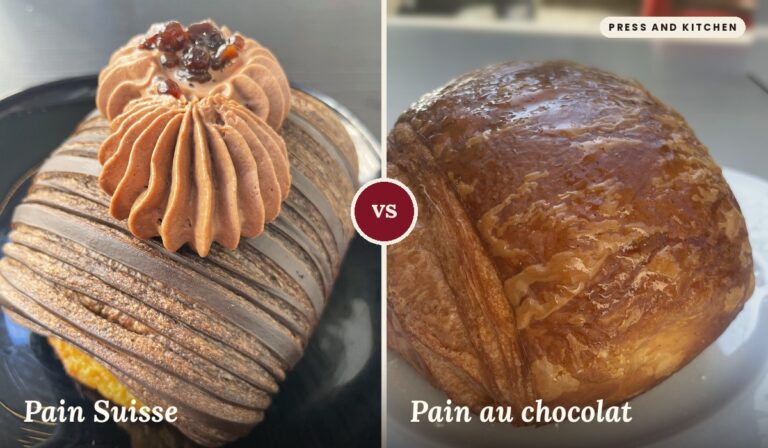 A sinistra, un Pain Suisse con sfoglia a strisce di cacao, decorato con due ciuffi di crema al cioccolato e piccoli cubetti di gelatina scura, su un piatto nero. A destra, un Pain au chocolat con la superficie dorata e lucida di glassa e la sfoglia stratificata ben visibile, su un piatto bianco.